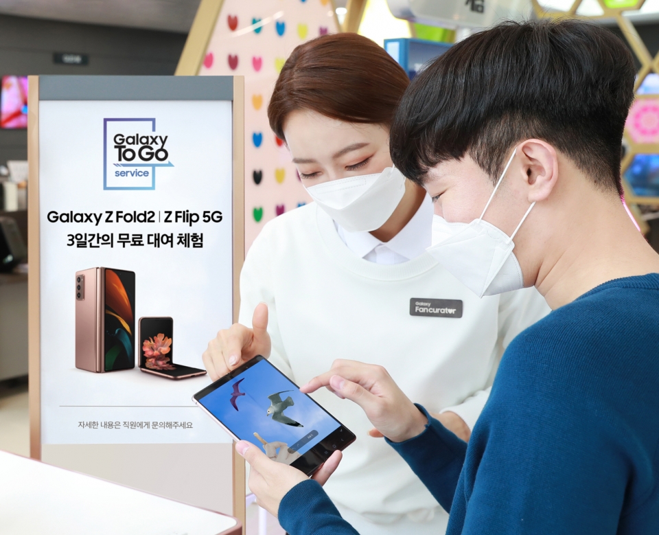서울 강남구 삼성 디지털프라자 도곡점에서 고객이 갤럭시 팬큐레이터의 안내를 받으며 '갤럭시 Z 폴드2' 로 '개체 지우기(AI 지우개)' 기능을 체험해보고 있다. [사진=삼성전자]